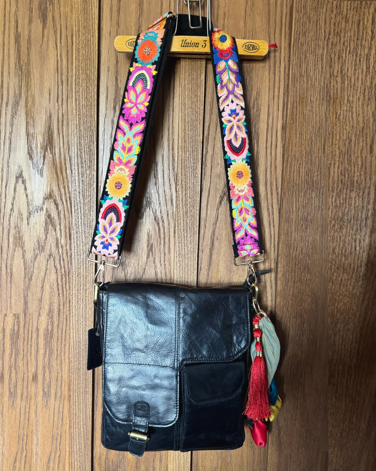 Leather bag with embroidered strap and decorative keychain
