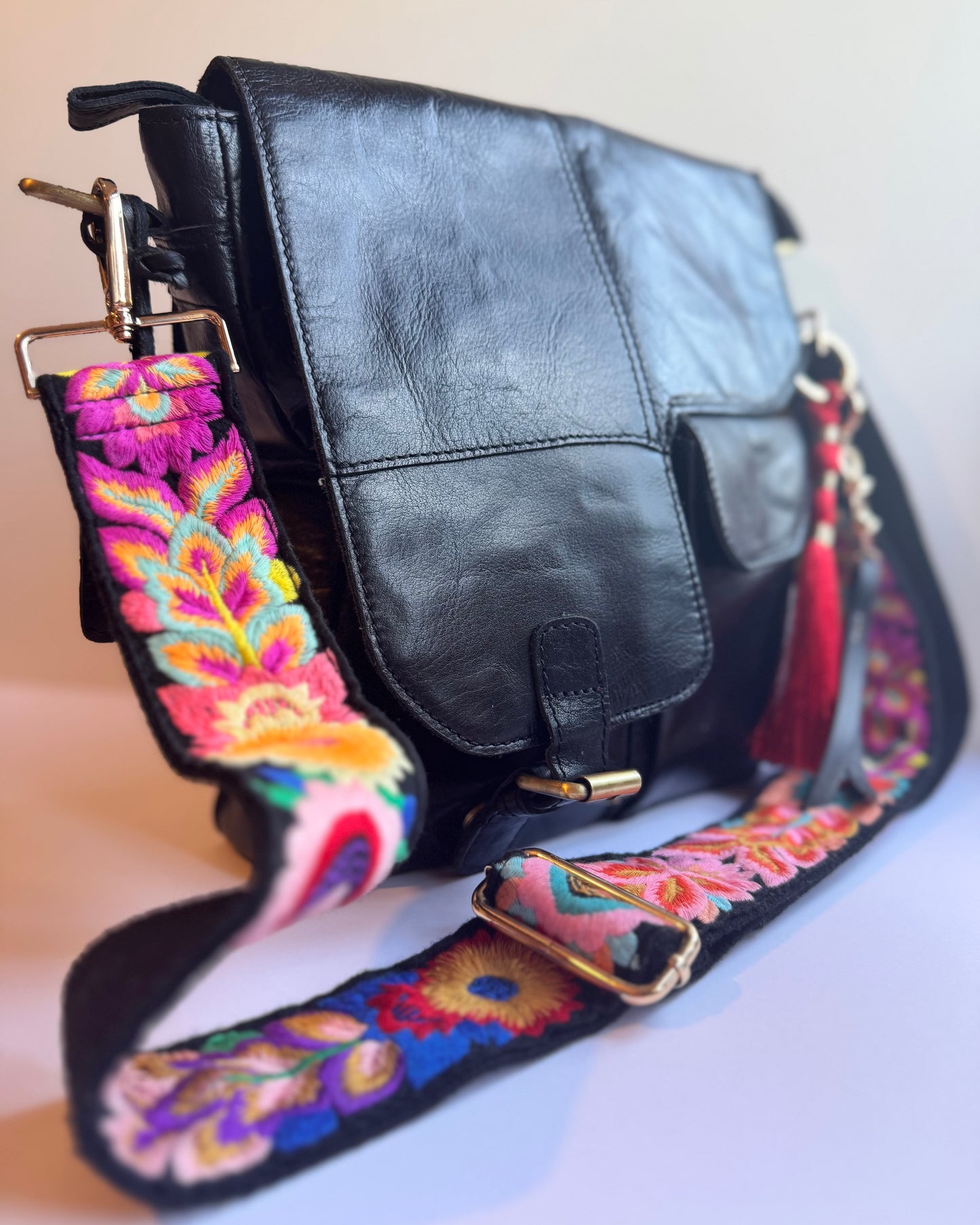 Leather bag with embroidered strap and decorative keychain
