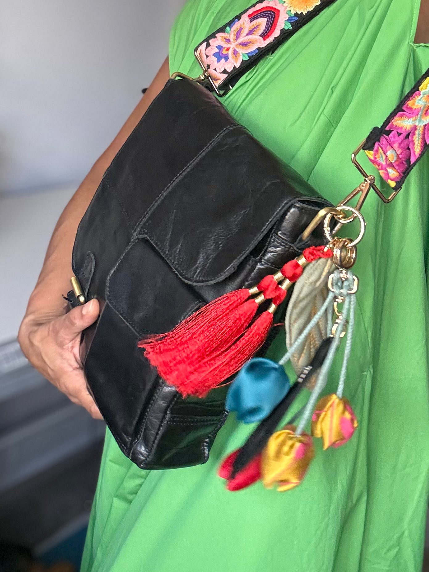 Leather bag with embroidered strap and decorative keychain