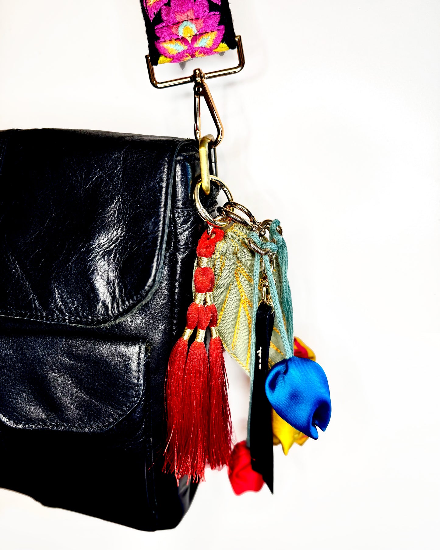 Leather bag with embroidered strap and decorative keychain
