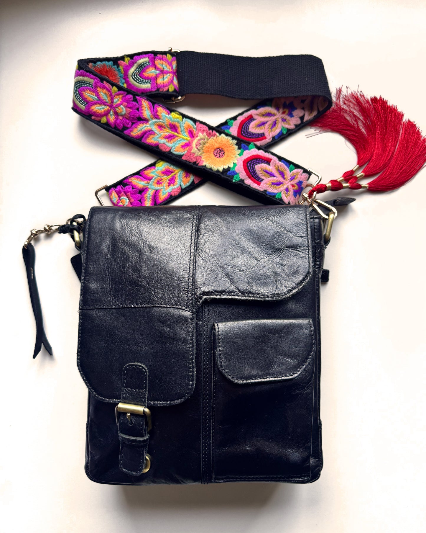 Leather bag with embroidered strap and decorative keychain