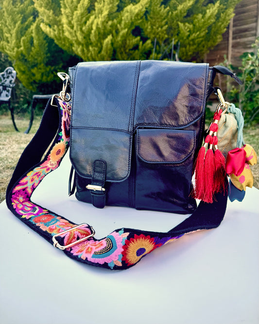 Leather bag with embroidered strap and decorative keychain