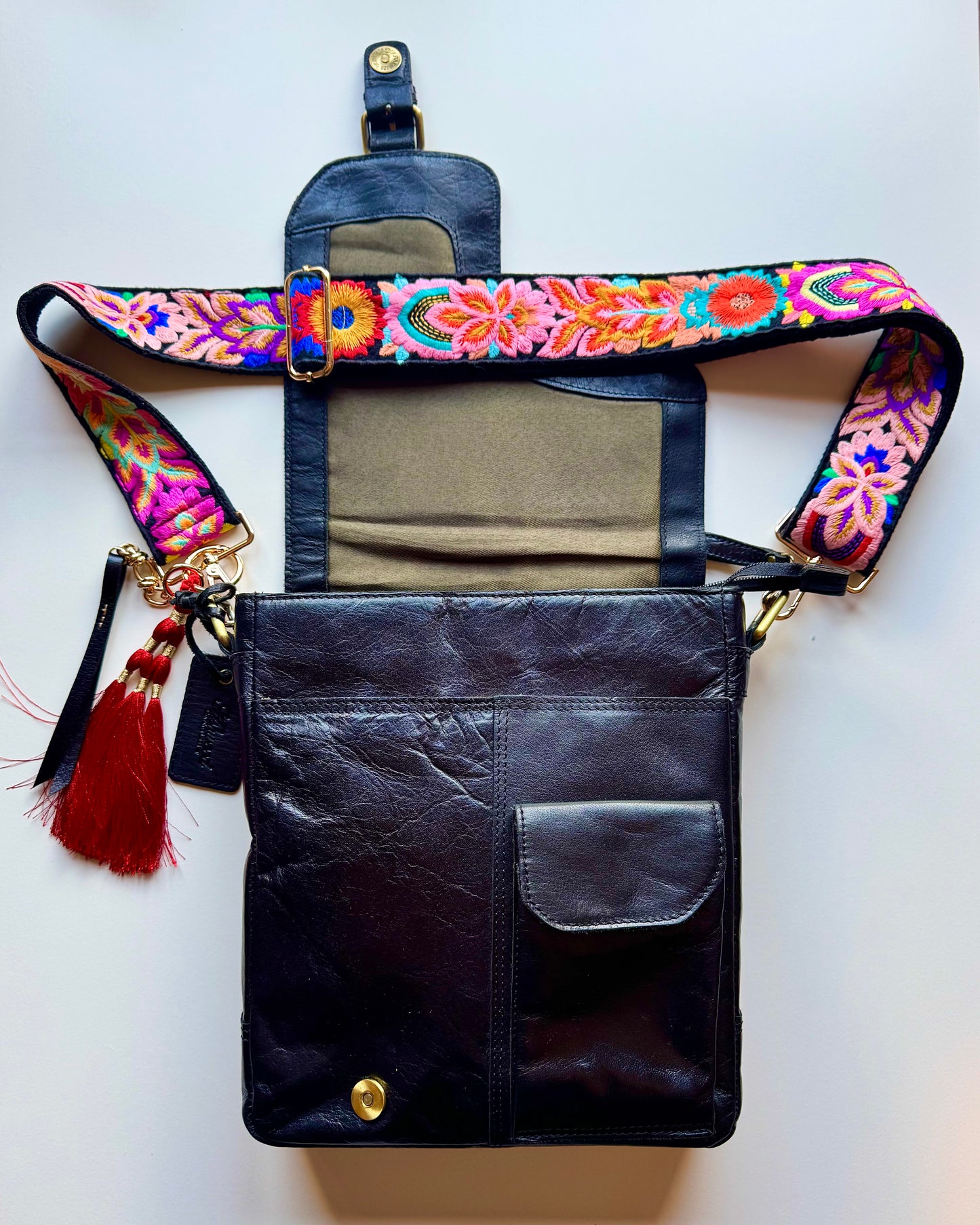 Leather bag with embroidered strap and decorative keychain